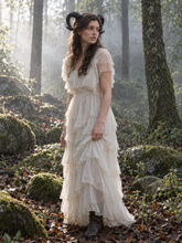 Load image into Gallery viewer, Full-body view of black curled ram horns worn by a model in a long white ruffled dress standing in a forest (AI-generated model image)